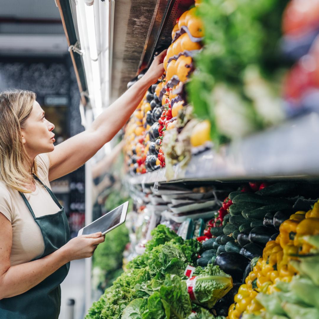 retail worker reaching for produce