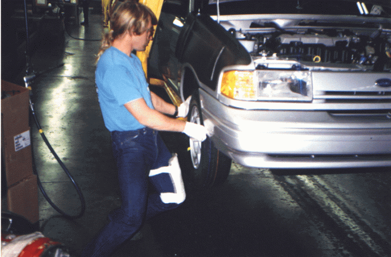 worker installing tire onto car 