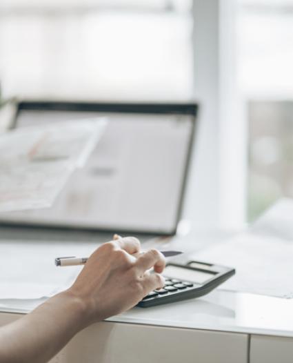 person using a calculator sitting at their laptop