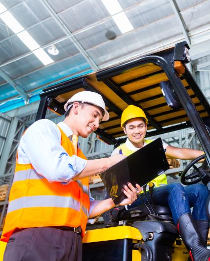 two people talking, one is sitting on a forklift