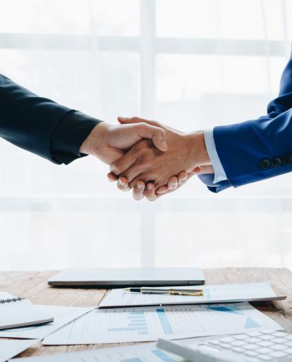 two people shaking hands over documents 