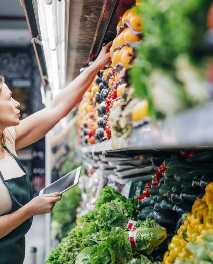 retail worker reaching for produce