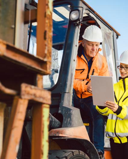 two workers talking beside machinery