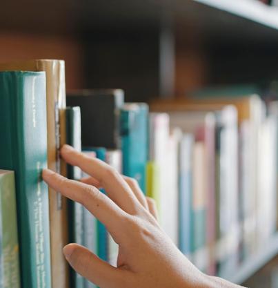 a hand reaching for a book on a shelf
