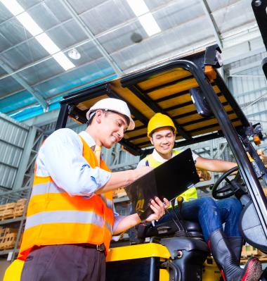 two people talking, one is sitting on a forklift