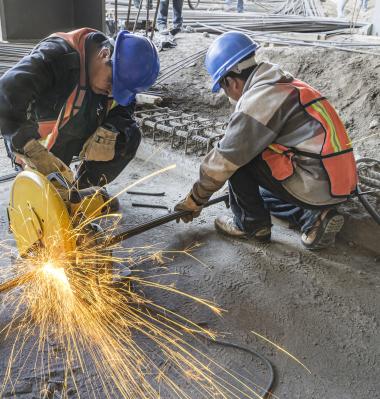 two construction workers kneeling down to ground level to complete their task