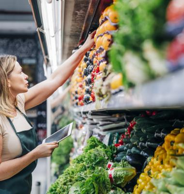 retail worker reaching for produce