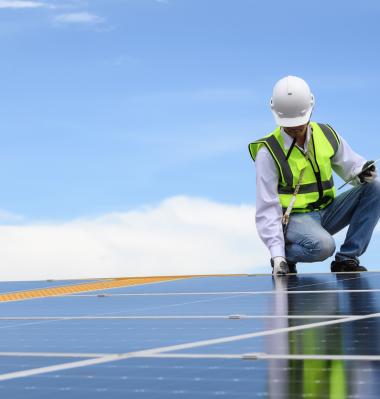 person kneeling to fix a solar panel