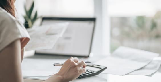 person using a calculator sitting at their laptop